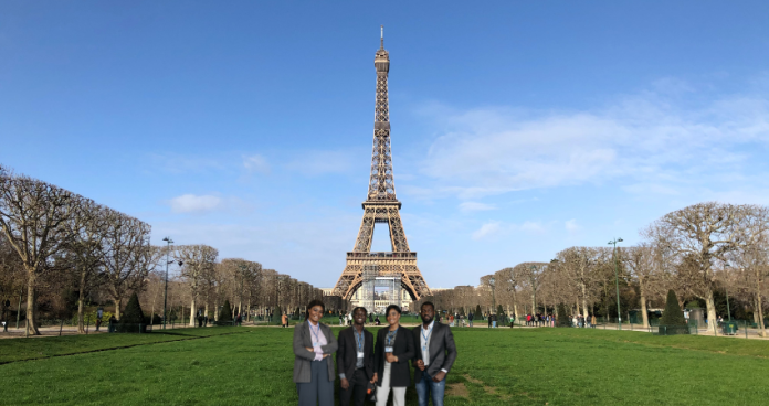 A professional with a conference badge standing by the Eiffel Tower.