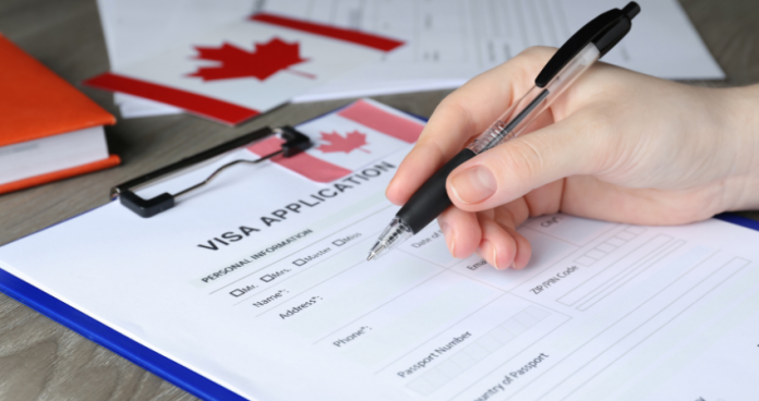 Person checking Canadian visa application documents on a desk.