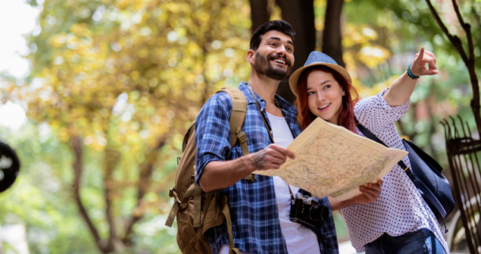 Couple planning their vacation together at a café, discussing destinations with a map and laptop.